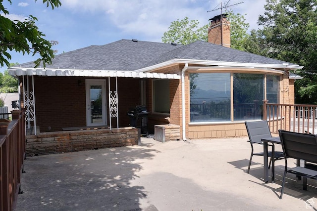 1444 S Beacon Dr E, Salt Lake City, UT 84108 - back of house with a shingled roof, a patio, brick siding, and a chimney