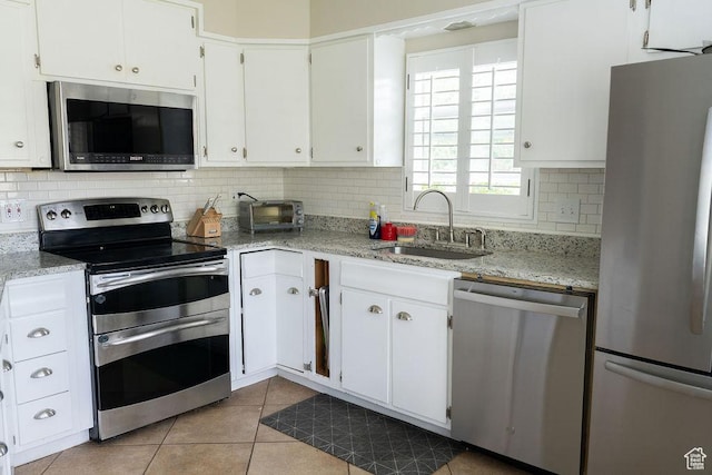 1444 S Beacon Dr E, Salt Lake City, UT 84108 - kitchen featuring stainless steel appliances, a sink, tasteful backsplash, light tile patterned flooring, and white cabinetry