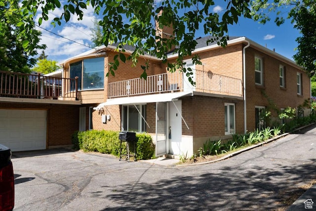 1444 S Beacon Dr E, Salt Lake City, UT 84108 - view of front of home with brick siding, driveway, a garage, and a balcony