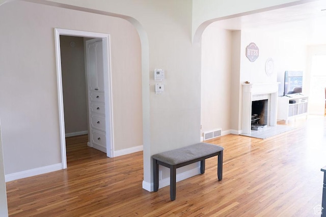 1444 S Beacon Dr E, Salt Lake City, UT 84108 - unfurnished living room featuring light wood-style floors, baseboards, arched walkways, and a fireplace with raised hearth