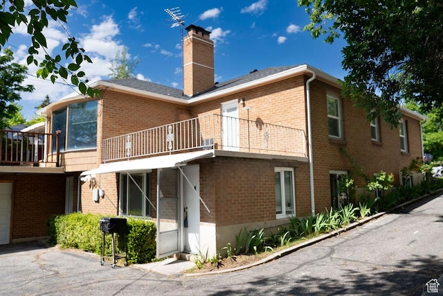 1444 S Beacon Dr E, Salt Lake City, UT 84108 - back of house featuring a chimney, a balcony, brick siding, and a sunroom