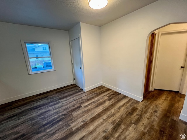 144 S 100 W, Tremonton, UT 84337 - unfurnished bedroom featuring dark wood-type flooring, arched walkways, baseboards, and a textured ceiling