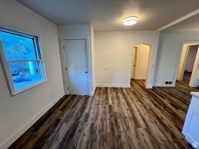 144 S 100 W, Tremonton, UT 84337 - unfurnished bedroom featuring arched walkways, dark wood-type flooring, baseboards, and a textured ceiling