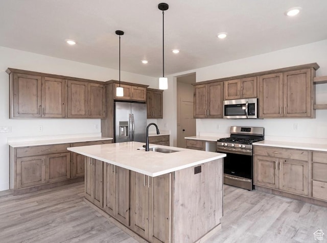 709 E 2450 N, North Logan, UT 84341 - kitchen featuring stainless steel appliances, a sink, light wood finished floors, decorative light fixtures, and an island with sink