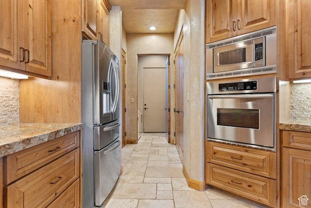 2405 W Entrada Trl Unit 76, St George, UT 84770 - kitchen featuring appliances with stainless steel finishes, stone tile floors, baseboards, backsplash, and light stone countertops