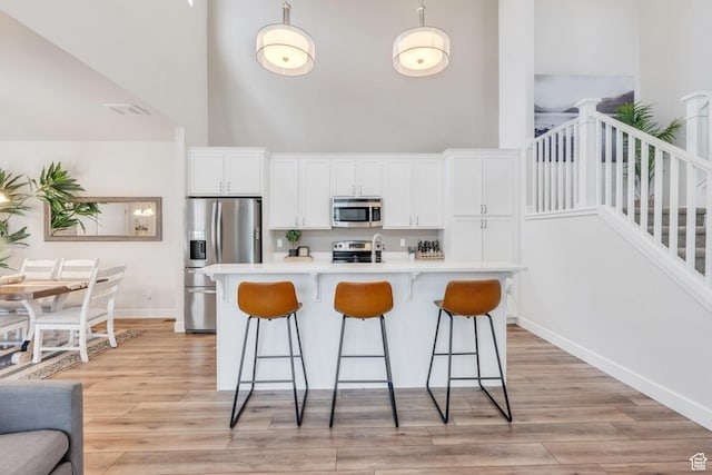 10394 S Crow Wing Dr, South Jordan, UT 84009 - kitchen featuring stainless steel appliances, a high ceiling, a kitchen bar, white cabinetry, and light countertops