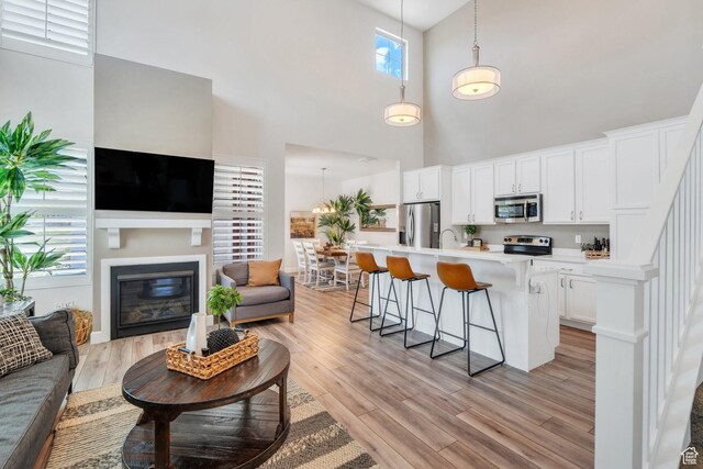 10394 S Crow Wing Dr, South Jordan, UT 84009 - living area featuring a towering ceiling, a glass covered fireplace, and light wood finished floors