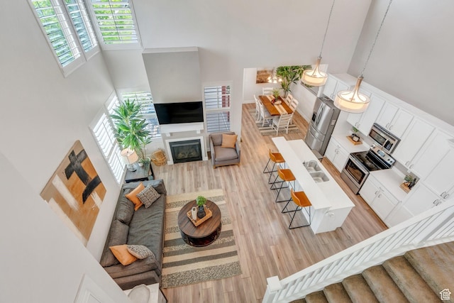 10394 S Crow Wing Dr, South Jordan, UT 84009 - living area featuring a towering ceiling, light wood finished floors, and a glass covered fireplace
