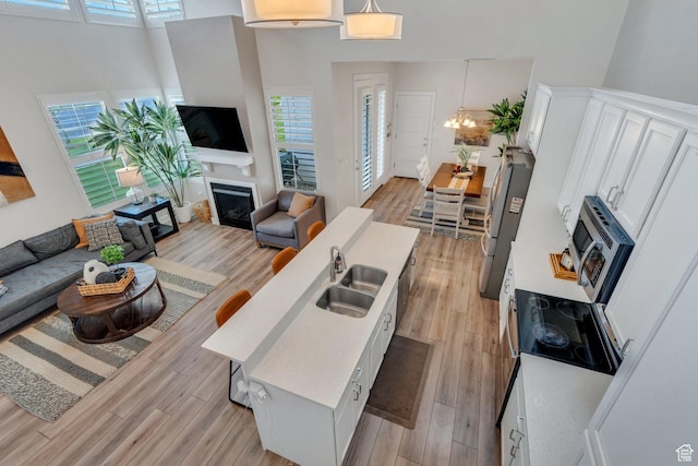 10394 S Crow Wing Dr, South Jordan, UT 84009 - living room featuring light wood finished floors, a chandelier, a fireplace, plenty of natural light, and a high ceiling