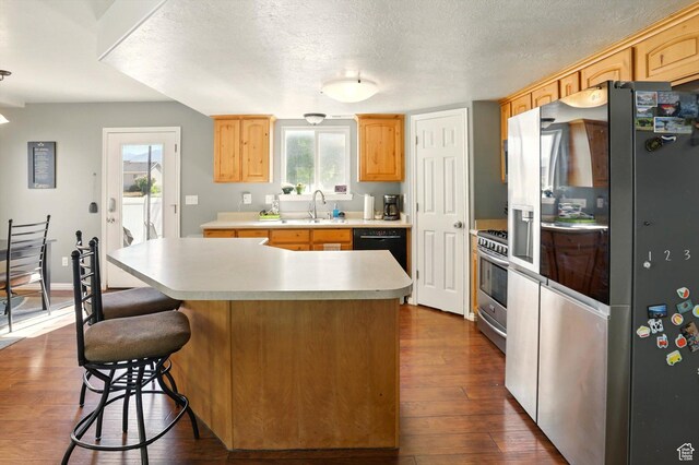 679 S Trail Cir W, Logan, UT 84341 - kitchen with stainless steel appliances, light countertops, dark wood-type flooring, a kitchen breakfast bar, and a kitchen island