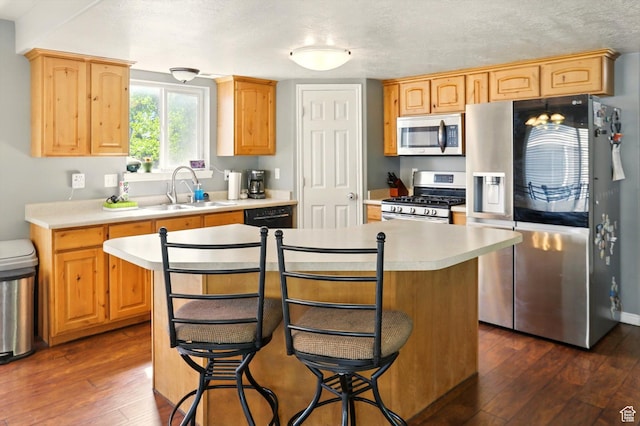 679 S Trail Cir W, Logan, UT 84341 - kitchen with appliances with stainless steel finishes, a sink, light countertops, dark wood-type flooring, and a breakfast bar area