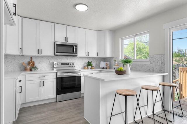 4112 W 5085 S, Kearns, UT 84118 - kitchen featuring appliances with stainless steel finishes, a kitchen breakfast bar, white cabinets, a textured ceiling, and light countertops