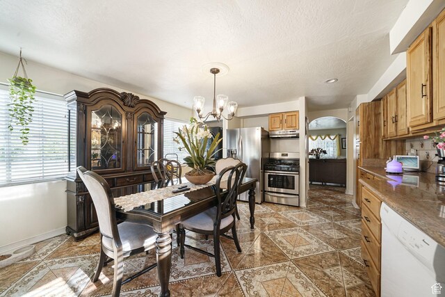 705 N American Beauty Dr, Salt Lake City, UT 84116 - dining area featuring a chandelier, arched walkways, a textured ceiling, baseboards, and light tile patterned floors