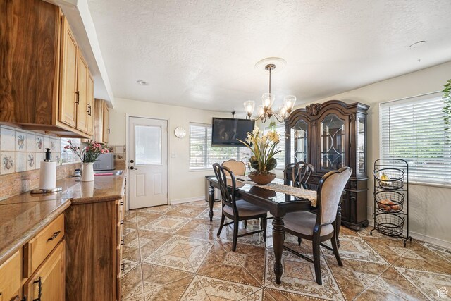 705 N American Beauty Dr, Salt Lake City, UT 84116 - dining space featuring a chandelier, baseboards, a textured ceiling, and light tile patterned flooring