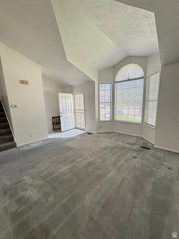 4853 W Ticklegrass Rd, West Jordan, UT 84081 - unfurnished living room featuring lofted ceiling, a textured ceiling, carpet flooring, baseboards, and stairway