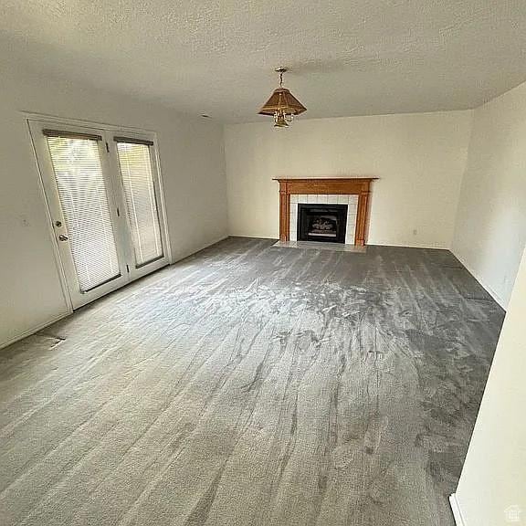 4853 W Ticklegrass Rd, West Jordan, UT 84081 - unfurnished living room featuring a tile fireplace and a textured ceiling