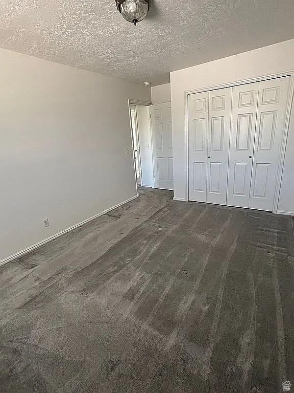4853 W Ticklegrass Rd, West Jordan, UT 84081 - unfurnished bedroom with a closet, a textured ceiling, baseboards, and dark wood-style flooring
