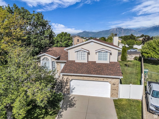 4853 W Ticklegrass Rd, West Jordan, UT 84081 - view of front facade featuring brick siding, concrete driveway, an attached garage, a chimney, and a mountain view