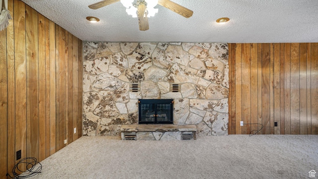374 N 500 E, Spanish Fork, UT 84660 - unfurnished living room featuring wood walls, carpet flooring, a textured ceiling, ceiling fan, and a stone fireplace
