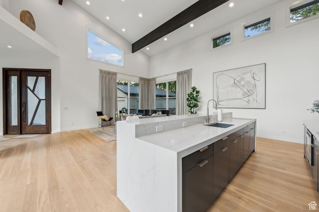 2067 E Pheasant Cir, Holladay, UT 84121 - kitchen with a sink, a high ceiling, light wood-type flooring, a center island with sink, and baseboards
