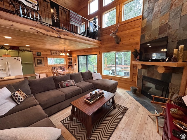 9281 N Uinta Dr Unit 348, Oakley, UT 84055 - living room featuring wood walls, hardwood / wood-style flooring, a large fireplace, a towering ceiling, and a chandelier