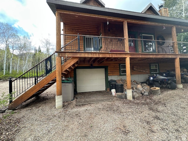 9281 N Uinta Dr Unit 348, Oakley, UT 84055 - rear view of house featuring stairway, a chimney, a garage, gravel driveway, and a deck