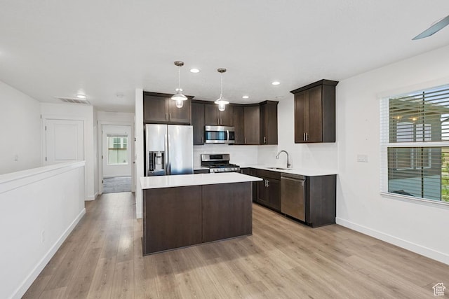 5957 W Lake Ave, South Jordan, UT 84009 - kitchen featuring appliances with stainless steel finishes, a sink, dark brown cabinets, light wood-style flooring, and light countertops
