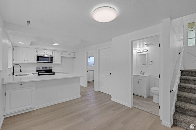 181 E 5150 S, Washington Terrace, UT 84405 - kitchen with appliances with stainless steel finishes, light wood-type flooring, a sink, light countertops, and white cabinets