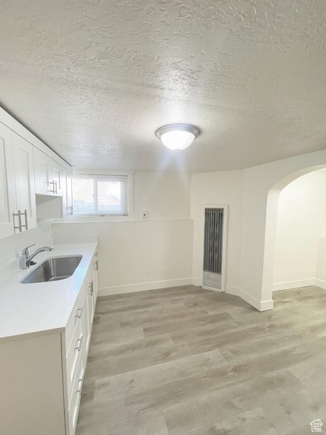 751 E Scott Ave, Millcreek, UT 84106 - kitchen with a sink, a textured ceiling, light wood-style floors, arched walkways, and white cabinetry