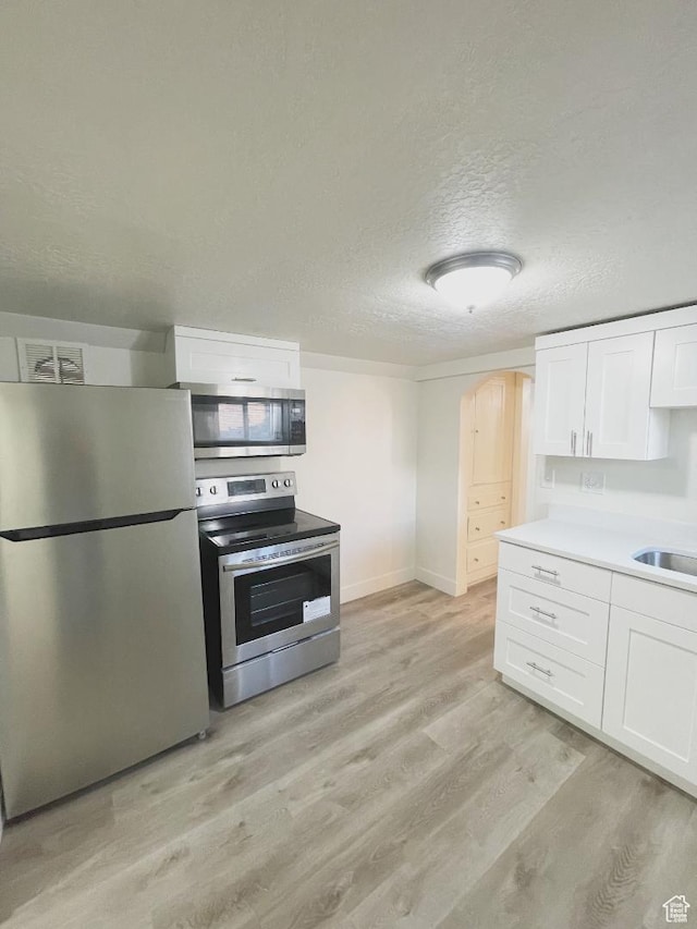 751 E Scott Ave, Millcreek, UT 84106 - kitchen featuring stainless steel appliances, light wood-style floors, white cabinets, a textured ceiling, and light countertops