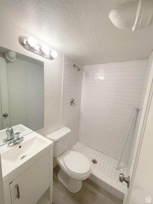 751 E Scott Ave, Millcreek, UT 84106 - bathroom featuring a tile shower, vanity, a textured ceiling, toilet, and wood finished floors