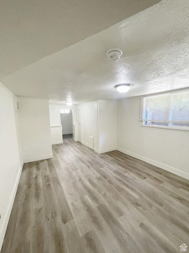 751 E Scott Ave, Millcreek, UT 84106 - below grade area with light wood-style flooring, baseboards, healthy amount of natural light, and a textured ceiling