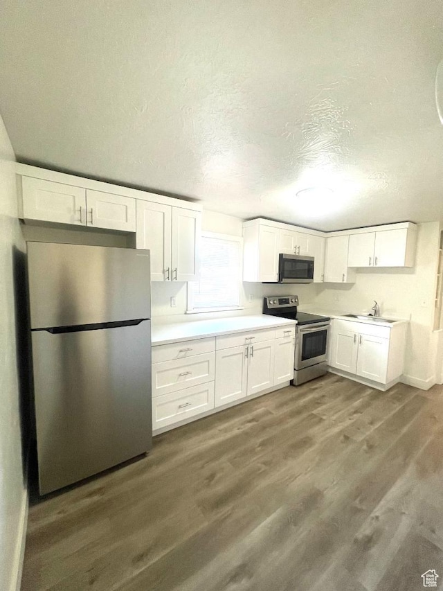 751 E Scott Ave, Millcreek, UT 84106 - kitchen featuring stainless steel appliances, white cabinetry, wood finished floors, a textured ceiling, and light countertops