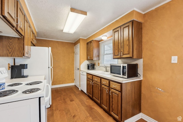 981 N Tremont St, Tremonton, UT 84337 - kitchen with white appliances, a sink, brown cabinets, wood finished floors, and baseboards