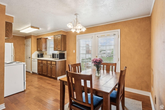 981 N Tremont St, Tremonton, UT 84337 - dining room with light wood-type flooring, a textured ceiling, a chandelier, ornamental molding, and a textured wall