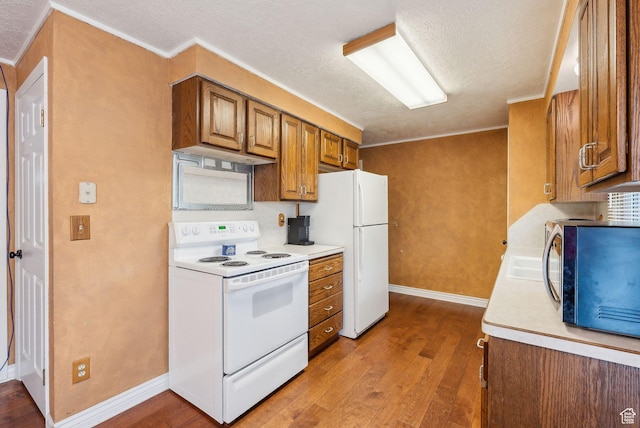 981 N Tremont St, Tremonton, UT 84337 - kitchen featuring white appliances, brown cabinetry, wood finished floors, a textured ceiling, and light countertops