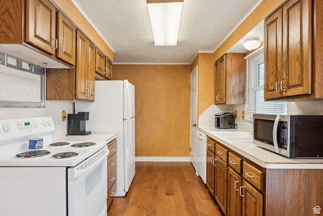 981 N Tremont St, Tremonton, UT 84337 - kitchen with white appliances, a sink, wood finished floors, brown cabinets, and a textured ceiling