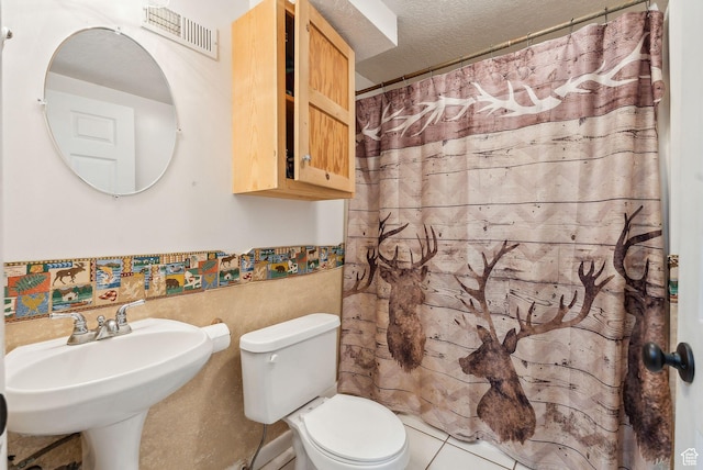 981 N Tremont St, Tremonton, UT 84337 - bathroom with toilet, curtained shower, a wainscoted wall, a textured ceiling, and tile walls