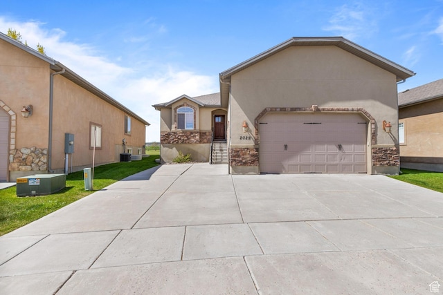 2029 S Cottage Ln, Garden City, UT 84028 - view of front of house featuring stucco siding, driveway, an attached garage, stone siding, and central air condition unit