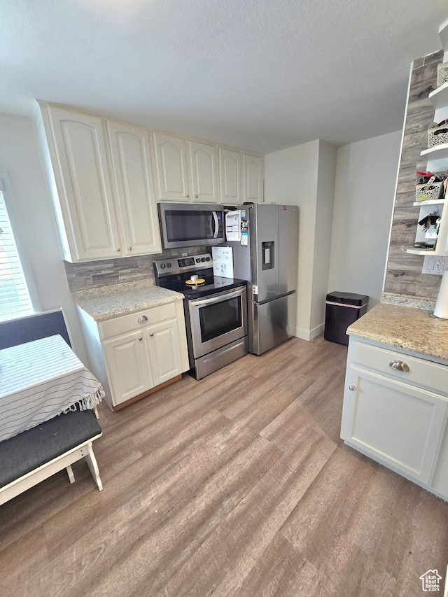 1191 N Geneva Rd, Provo, UT 84601 - kitchen with appliances with stainless steel finishes, light wood-type flooring, white cabinets, baseboards, and a textured ceiling