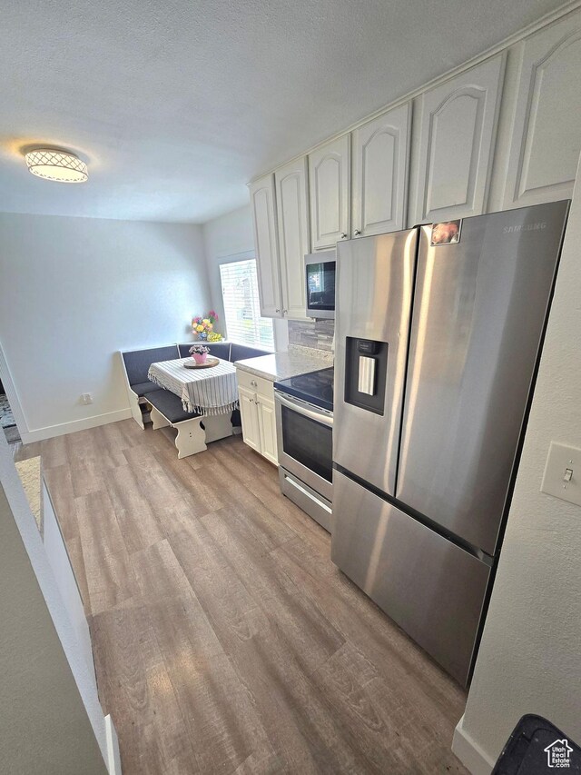 1191 N Geneva Rd, Provo, UT 84601 - kitchen with stainless steel appliances, light wood finished floors, white cabinets, light countertops, and baseboards