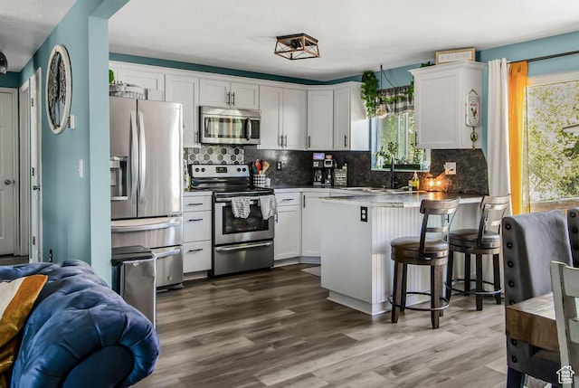 3631 W 7910 S, West Jordan, UT 84088 - kitchen with stainless steel appliances, a sink, a peninsula, white cabinets, and decorative backsplash