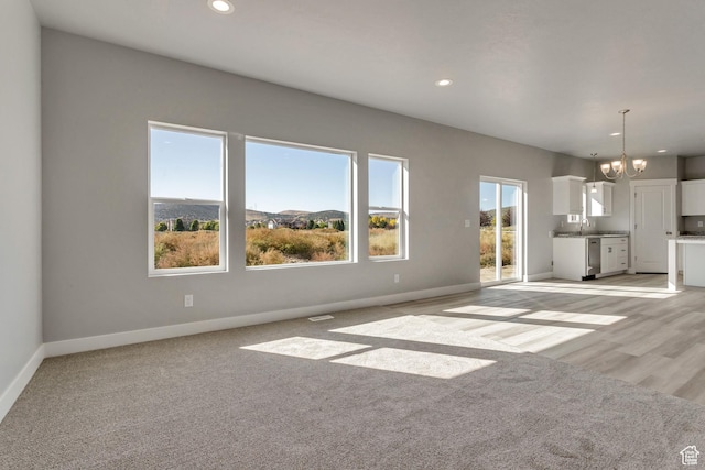 5452 N Orville St Unit 411, Eagle Mountain, UT 84005 - unfurnished living room featuring a chandelier, recessed lighting, baseboards, a sink, and light colored carpet