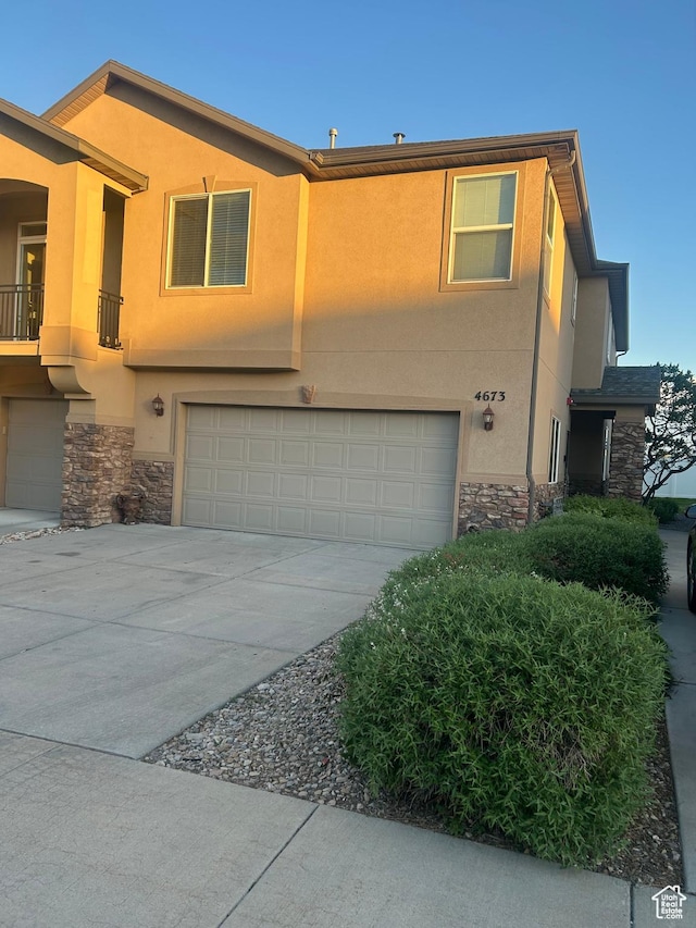 4673 W Greensand Dr, West Jordan, UT 84084 - view of front facade featuring stone siding, a garage, and stucco siding