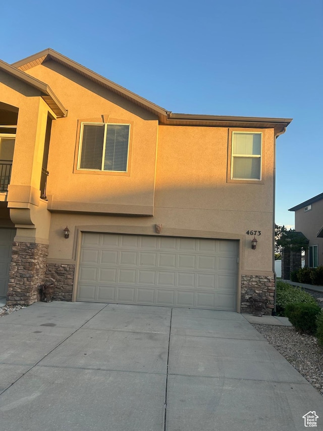 4673 W Greensand Dr, West Jordan, UT 84084 - view of front of home with stone siding, an attached garage, driveway, and stucco siding