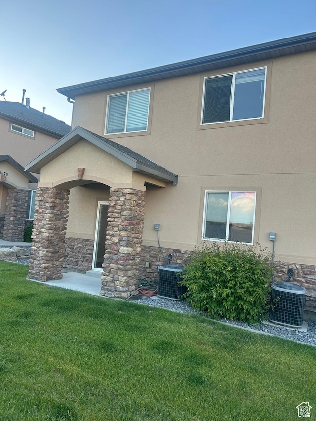 4673 W Greensand Dr, West Jordan, UT 84084 - rear view of property featuring stucco siding, central AC unit, stone siding, and a lawn