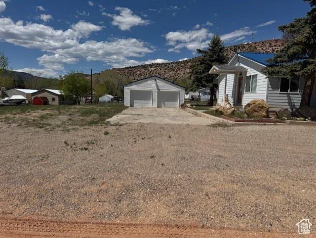 345 N 1st E, Manila, UT 84046 - view of side of property featuring a mountain view, a detached garage, an outdoor structure, and driveway