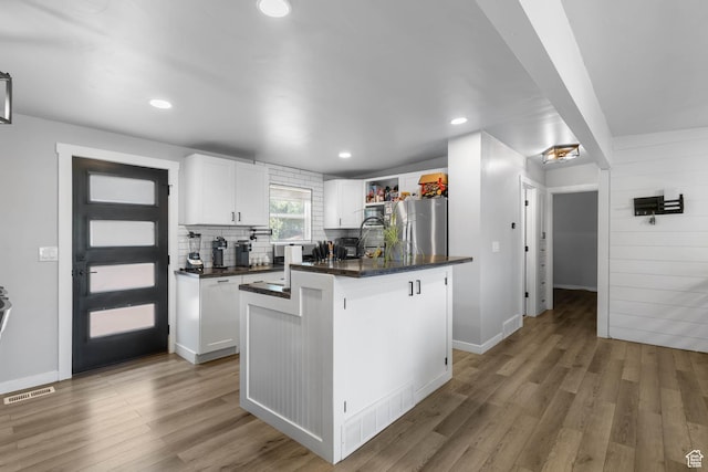 4206 S Whipoorwhil St W, West Valley City, UT 84120 - kitchen with freestanding refrigerator, dark countertops, white cabinets, light wood-type flooring, and backsplash