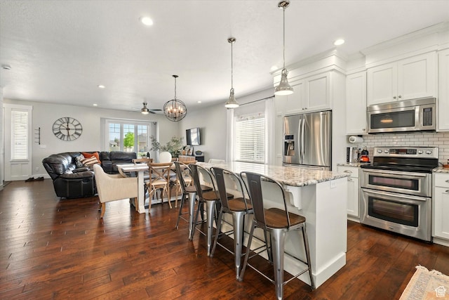 2986 S Stonebridge Dr W, Nibley, UT 84321 - kitchen featuring stainless steel appliances, open floor plan, light stone countertops, backsplash, and dark wood-type flooring