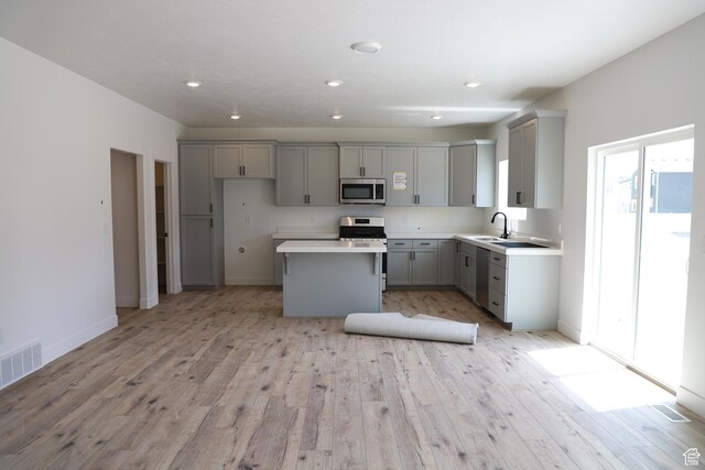 3711 N Janie St Unit 1015, Eagle Mountain, UT 84005 - kitchen with stainless steel appliances, gray cabinets, a sink, a center island, and light wood-type flooring